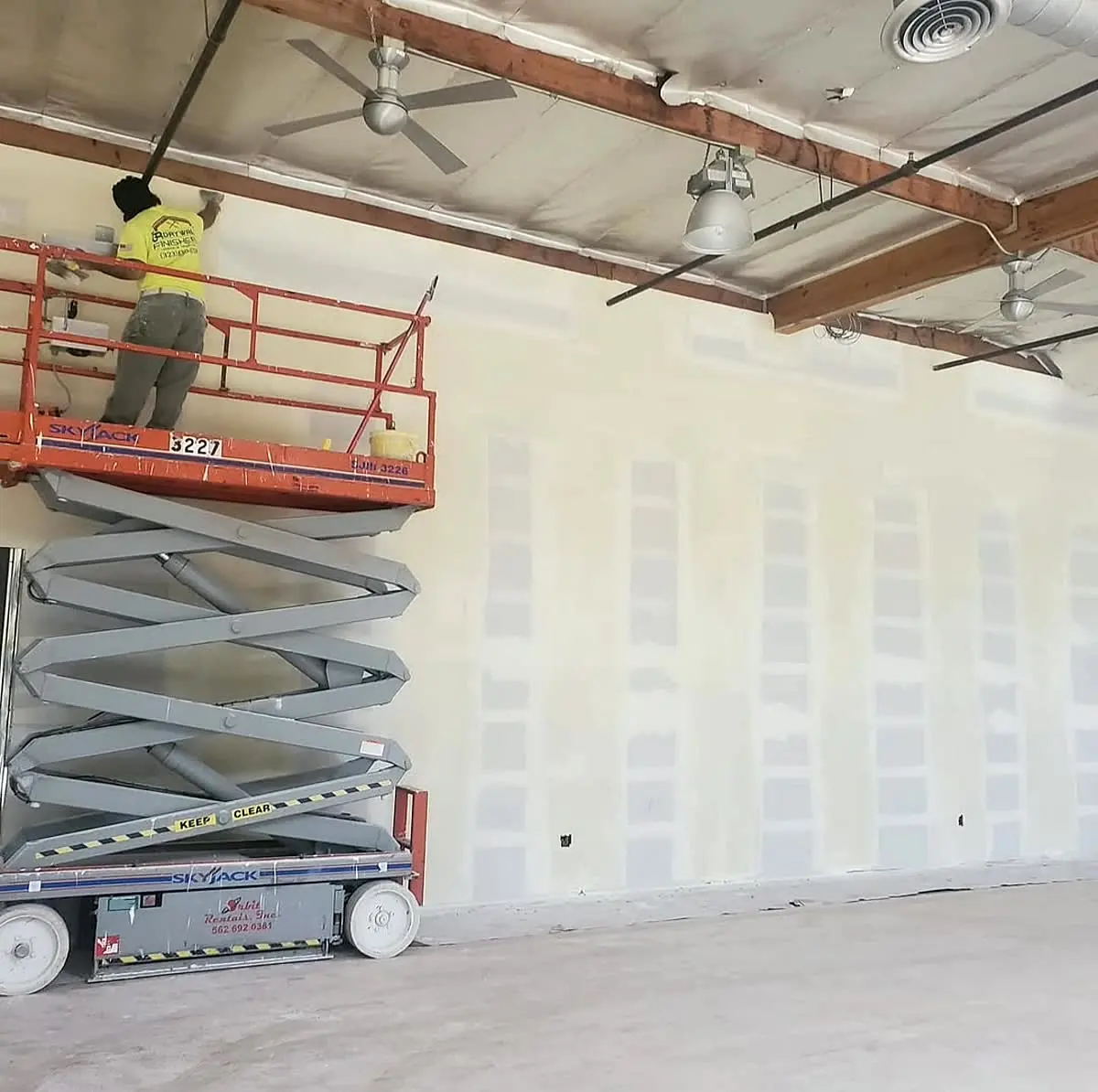 Commercial drywall wall being finished from a scissor lift — Ceiling Install